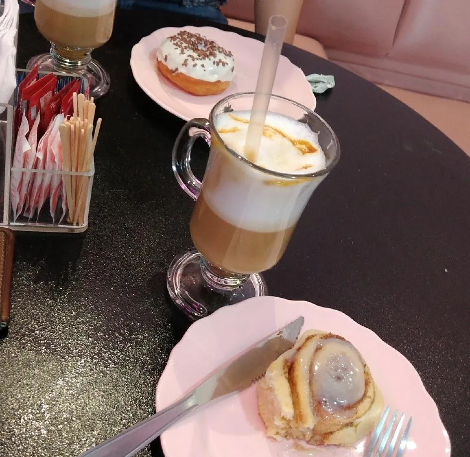 Mesa com capuccino e rocambole no prato rosa
